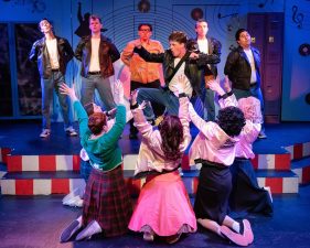 Alameda Post - In Altarena's Grease, female characters excitedly cheer for a musician and band on a platform onstage