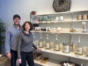 Alameda Post - the husband and wife team behind Replenish Marketplace stands with shelves of products, including large pump containers.