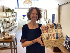 Alameda Post - a woman stands and smiles while holding merchandise in Replenish Marketplace