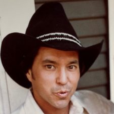 Alameda Post - a young adult John D. Fernandez, Jr. holds a bottle and wears a cowboy hat