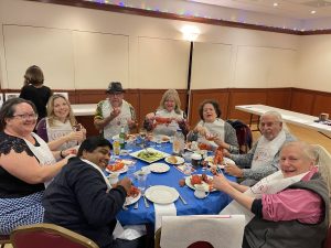 Alameda Post - a table full of smiling people eating lobster at the Rotary Club Lobster Dinner