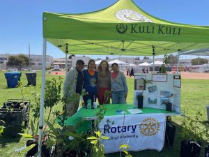 Alameda Post - a group of four people smile and pose at a Rotary Club of Alameda booth at the Spring Shindig