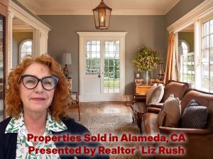 Alameda Post - A red haired woman smiles the living room of a home for sale.
