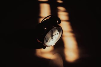 Alameda Post - an old fashioned analog alarm clock in shadows