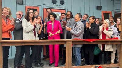 Alameda Post - Mayor Ashcraft cuts a ribbon at Dignity Village, surrounded by smiling and clapping people